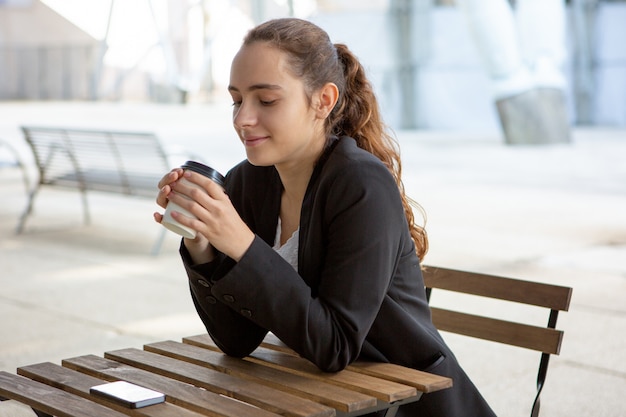 Lächelnder ruhiger Student, der Kaffeepause genießt