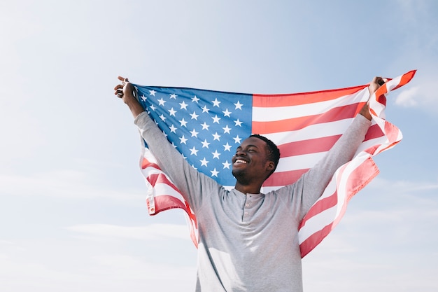 Lächelnder schwarzer Mann, der wellenartig bewegende Flagge hält