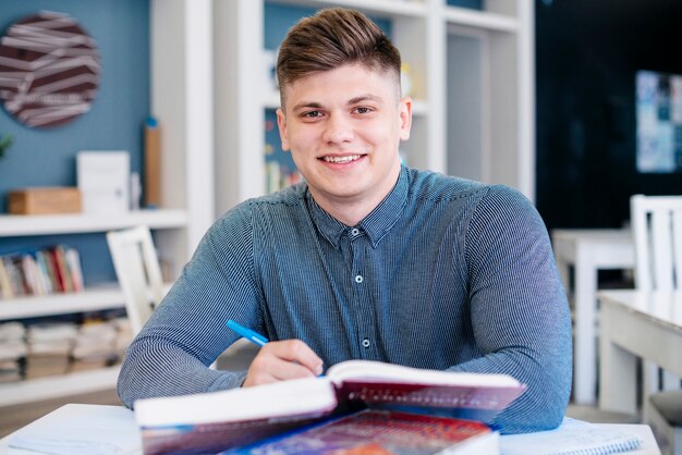 Lächelnder Student, der in der Bibliothek studiert