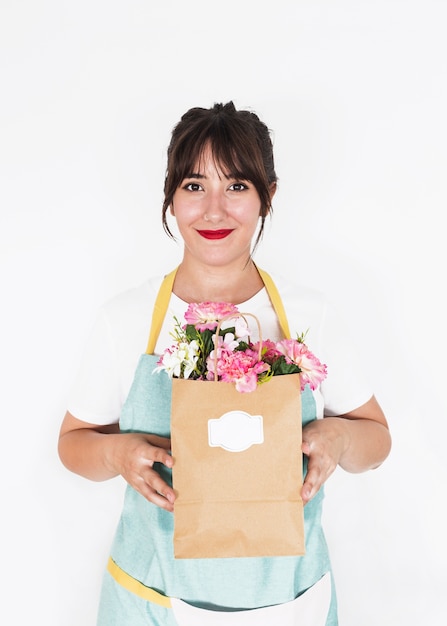 Lächelnder weiblicher Florist, der voll Papiertüte frische Blumen hält