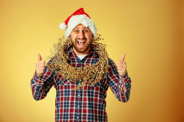 Lächelnder Weihnachtsmann, der eine Weihnachtsmütze auf dem orangefarbenen Studiohintergrund trägt