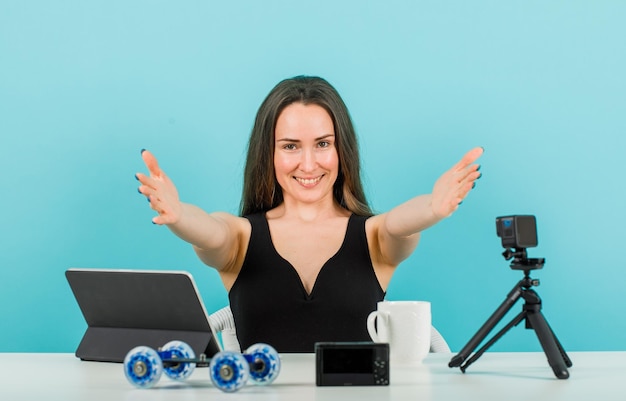 Lächelndes Bloggermädchen streckt Hände zur Kamera auf blauem Hintergrund aus
