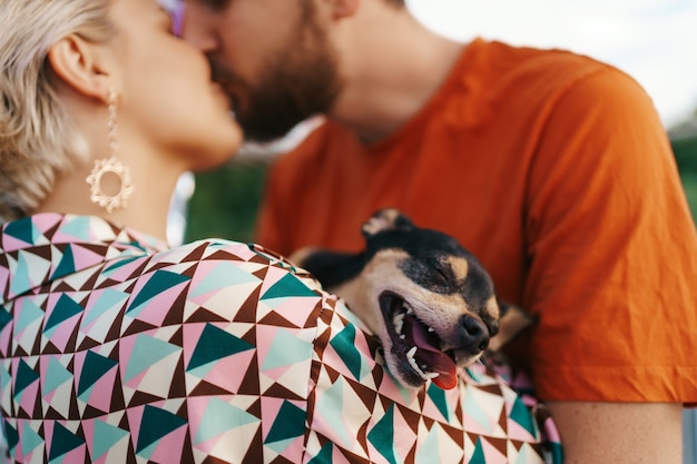 Lächelndes hundegesicht, während seine menschen es küssen und es umarmen