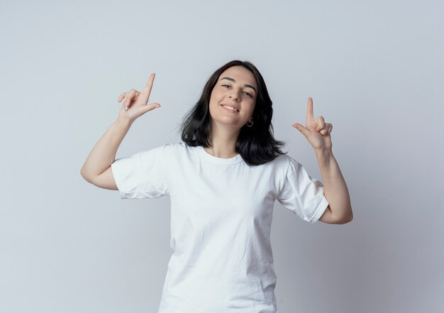 Lächelndes junges hübsches kaukasisches Mädchen, das mit den Fingern oben lokalisiert auf weißem Hintergrund mit Kopienraum zeigt