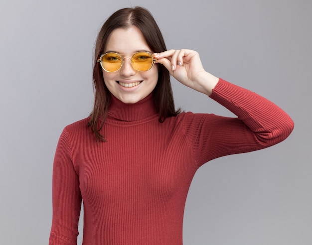 Lächelndes junges hübsches mädchen, das eine sonnenbrille trägt und greift