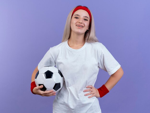 Lächelndes junges kaukasisches sportliches Mädchen mit Zahnspangen, die Stirnband tragen