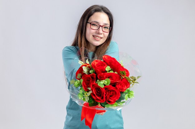 Lächelndes junges Mädchen am Valentinstag, das Blumenstrauß in die Kamera hält, isoliert auf weißem Hintergrund