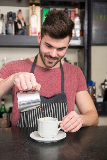 Lächelndes junges männliches barista bereiten Kaffee zu