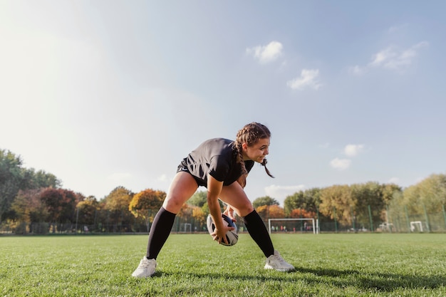 Lächelndes Mädchen, das mit einem Rugbyball spielt