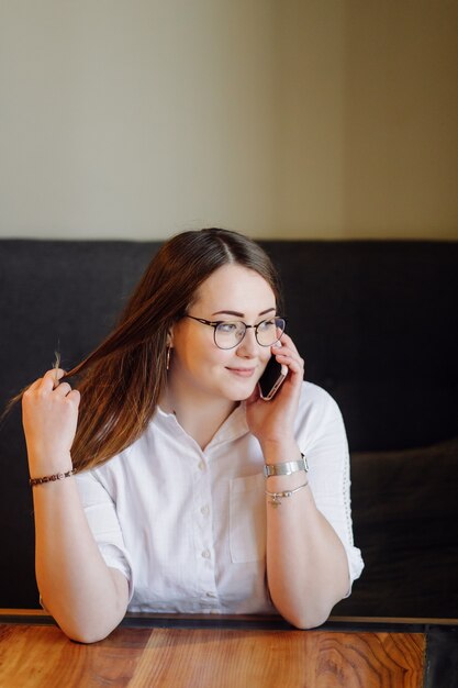 Lächelndes Mädchen, das Zeit in einem Straßencafé mit digitalem Gerät verbringt