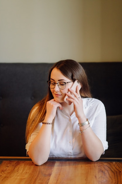 Lächelndes Mädchen, das Zeit in einem Straßencafé mit digitalem Gerät verbringt