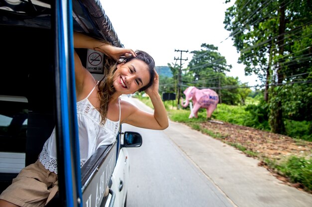 lächelndes Mädchen schaut aus dem Fenster eines Taxis, Tuk-Tuk-Reisekonzepts