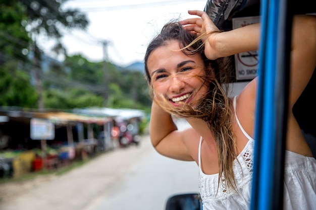 Kostenloses Foto lächelndes mädchen schaut aus dem fenster eines taxis, tuk-tuk