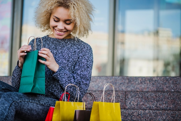 Lächelndes Mädchen sitzt mit Taschen