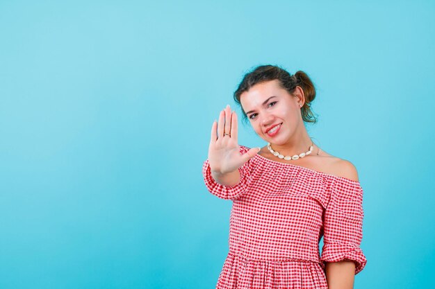 Lächelndes Mädchen zeigt ihre Handvoll zur Kamera auf blauem Hintergrund