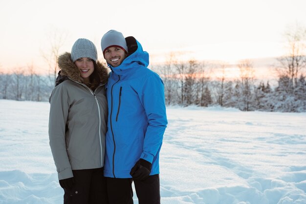 Lächelndes Paar, das auf verschneite Landschaft steht
