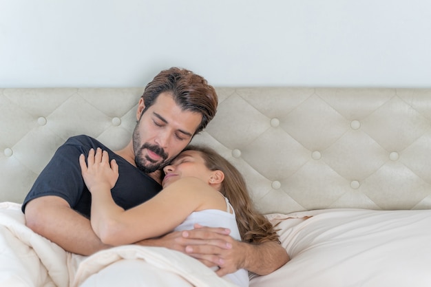 lächelndes Paar entspannt sich und Paare kuscheln im Bett