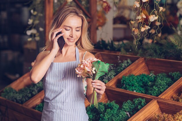 Lächelndes Porträt einer Floristenrosahortensie in der Hand, die am Handy spricht