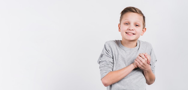 Lächelndes porträt eines jungen, der die hände schaut zur kamera gegen weißen hintergrund verbindet