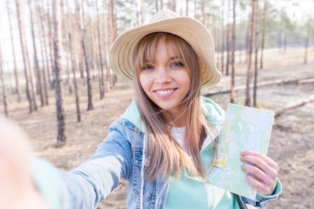 Lächelndes Porträt eines Mädchens, das in der Hand die Karte nimmt selfie am Handy hält