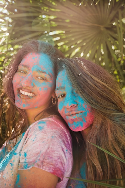 Lächelndes Porträt von junge Frauen mit holi Farbe auf ihrem Gesicht, das Kamera betrachtet