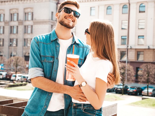 Lächelndes schönes Mädchen und ihr hübscher Freund in der zufälligen Sommerkleidung. . Frau mit einer Flasche Wasser