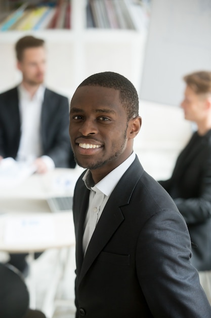Lächelndes vertikales Porträt des tragenden Anzugs Headshot des afrikanischen Geschäftsmannes mit Team
