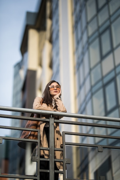 Lässig gekleidet Schöne Frau mit Sonnenbrille bleibt auf der Brücke