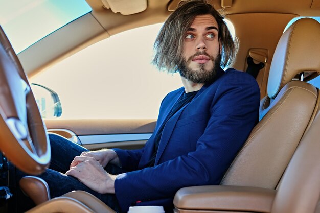 Lässiger bärtiger Mann mit langen Haaren in einem Auto.