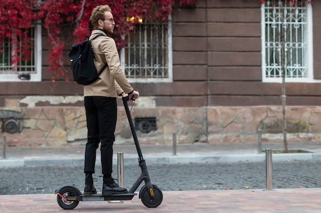 Lässiger Mann, der mit seinem Elektroroller reitet