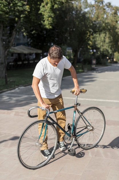 Lässiger Mann der Vorderansicht, der sein Fahrrad prüft