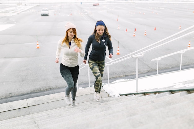 Läufer mit zwei Frauen, der auf dem Treppenhaus im Winter rüttelt