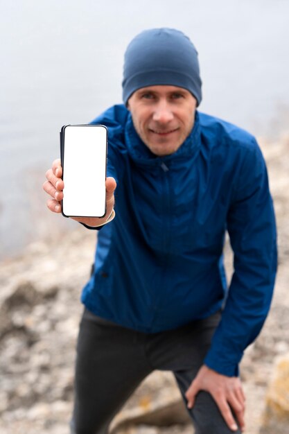Läufer zeigt leeres Telefon in der Natur