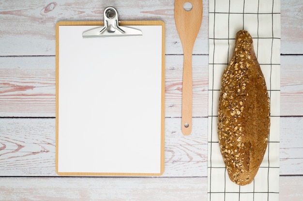 Kostenloses Foto laib brot auf serviette; spachtel und papier in zwischenablage über dem holzschreibtisch