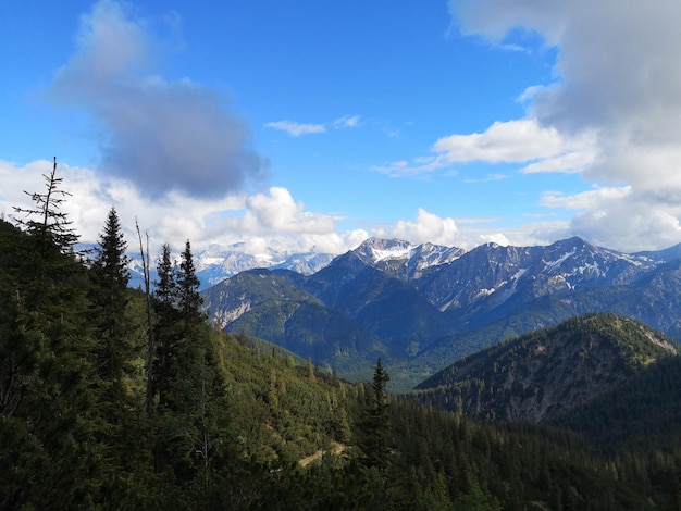 Landschaft aus felsigen Hügeln, die im Sonnenlicht und einem blauen bewölkten Himmel mit viel Grün bedeckt sind