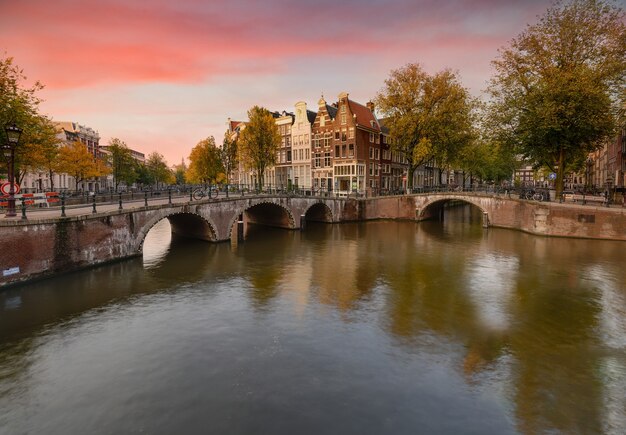 Landschaft des Keizersgrachtkanals in Amsterdam mit dem Spiegelbild von Gebäuden und grünen Bäumen