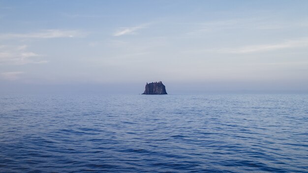 Landschaft des Meeres mit einem Felsen unter einem bewölkten Himmel während des Tages