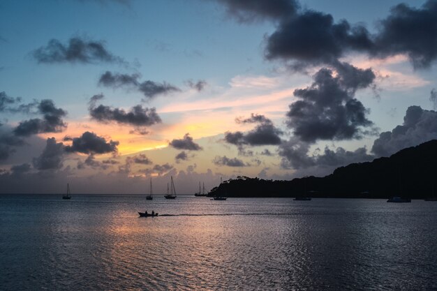 Landschaft des Sonnenuntergangs mit einer Silhouette von Berg und Booten im Meer