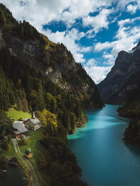 Landschaft eines schönen Flusses zwischen den Bergen und kleinen Häusern unter dem bewölkten Himmel