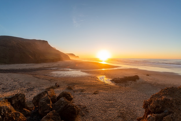 Landschaft eines Ufers, umgeben von Bergen und Meer unter einem blauen Himmel während des Sonnenuntergangs