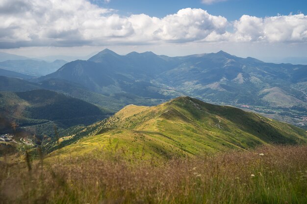 Landschaft von Hügeln bedeckt im Grünen mit felsigen Bergen unter einem bewölkten Himmel auf dem