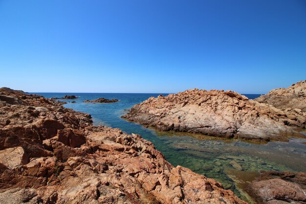 Landschaftsaufnahme einer Küste mit großen Felsen in einem klaren blauen Himmel