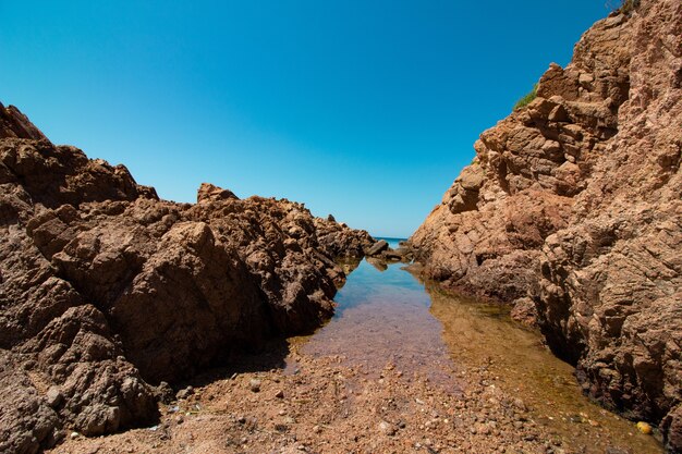 Landschaftsaufnahme von großen Felsen in einem offenen Meer mit einem klaren sonnigen blauen Himmel