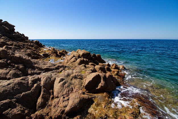 Landschaftsaufnahme von großen Grundgesteinen in einem offenen blauen Meer mit einem klaren sonnigen blauen Himmel