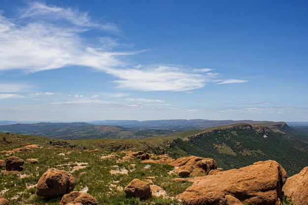 Landschaftsaufnahme von wunderschönen Bergen mit Wäldern unter blauem Himmel mit Wolken