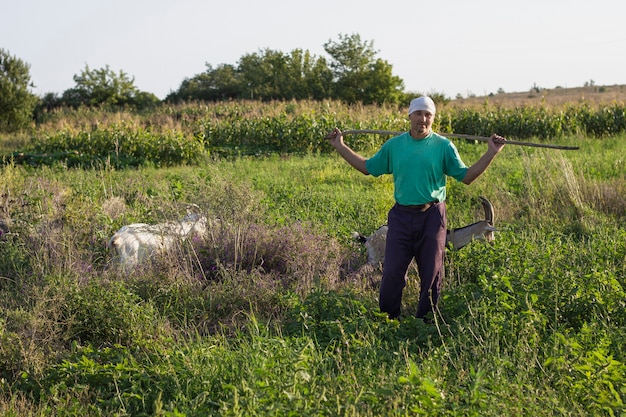 Kostenloses Foto landwirt, der kamera beim aufpassen von ziegen betrachtet