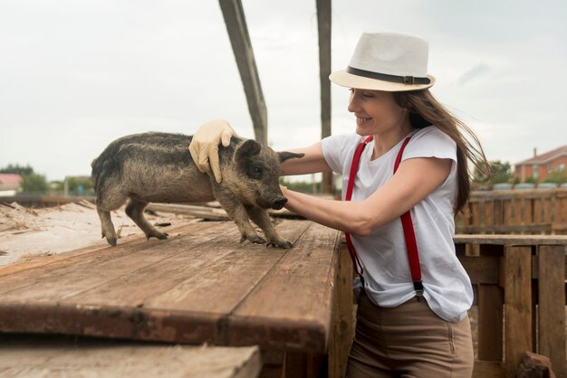 Landwirt, der um Schweinen in einem Schweinestall sich kümmert