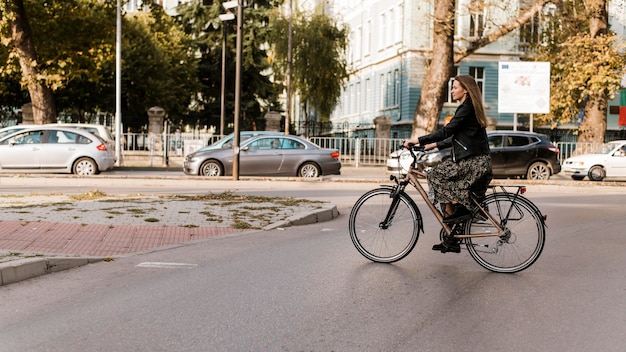 Lange Ansicht der Frau, die das Fahrrad reitet