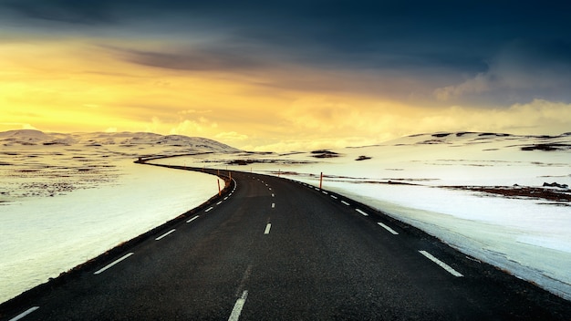 lange gerade Straße bei Sonnenuntergang im Winter.