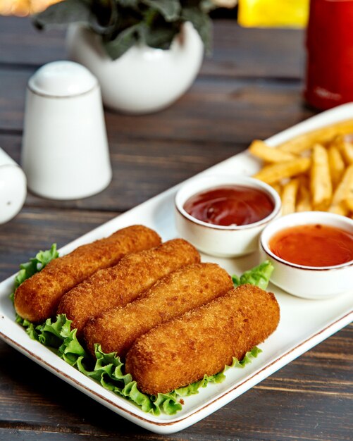 Lange Hühnernuggets, serviert mit Pommes Ketchup und süßer Chilisauce